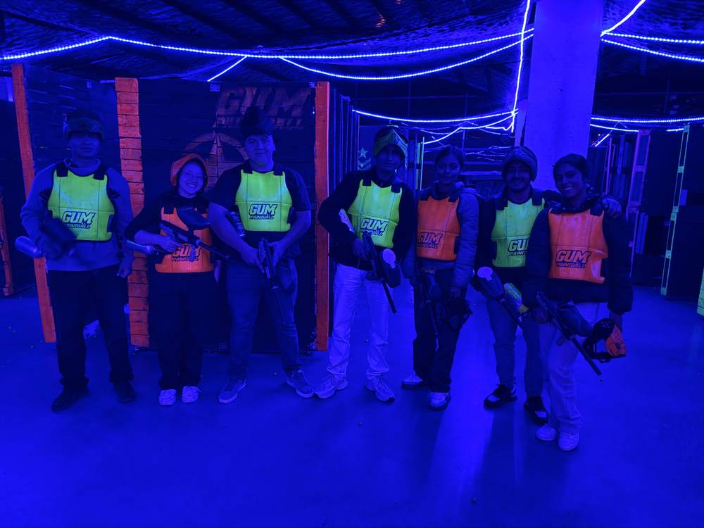 Equipo listo para jugar paintball bajo luces neón azules en GUM Paintball